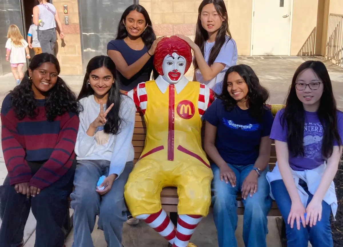 ProjectPatho members sitting with the Ronald McDonald statue outside Ronald McDonald House Charities