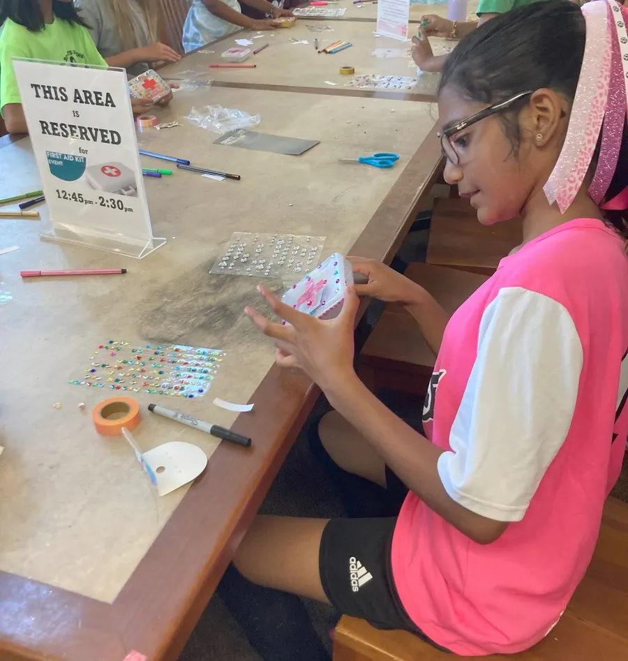 A student decorates her first aid kit with stickers and gems