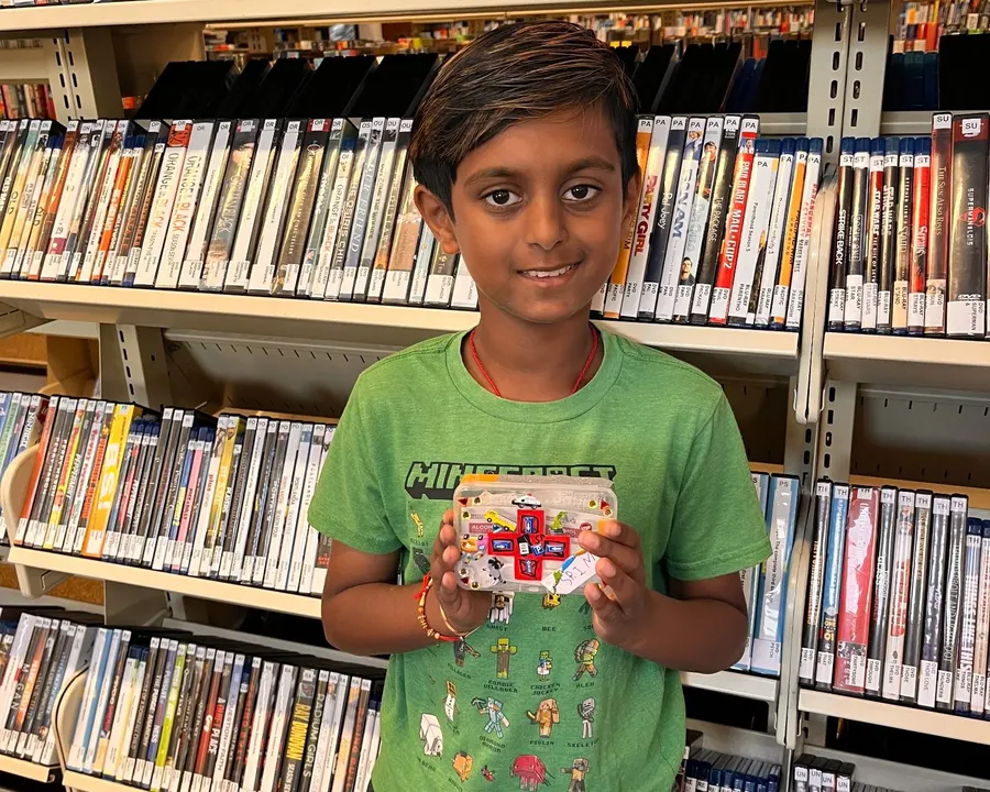 A student in a green shirt shows off his finished first aid kit
