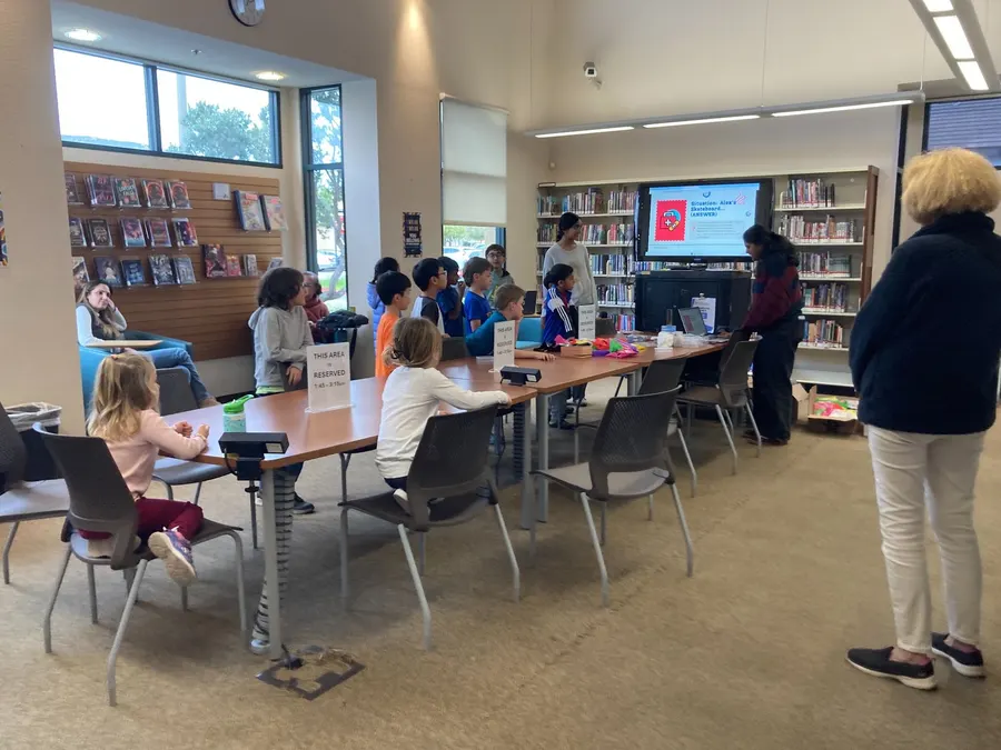 The library room set up for the first aid workshop, with families at the tables