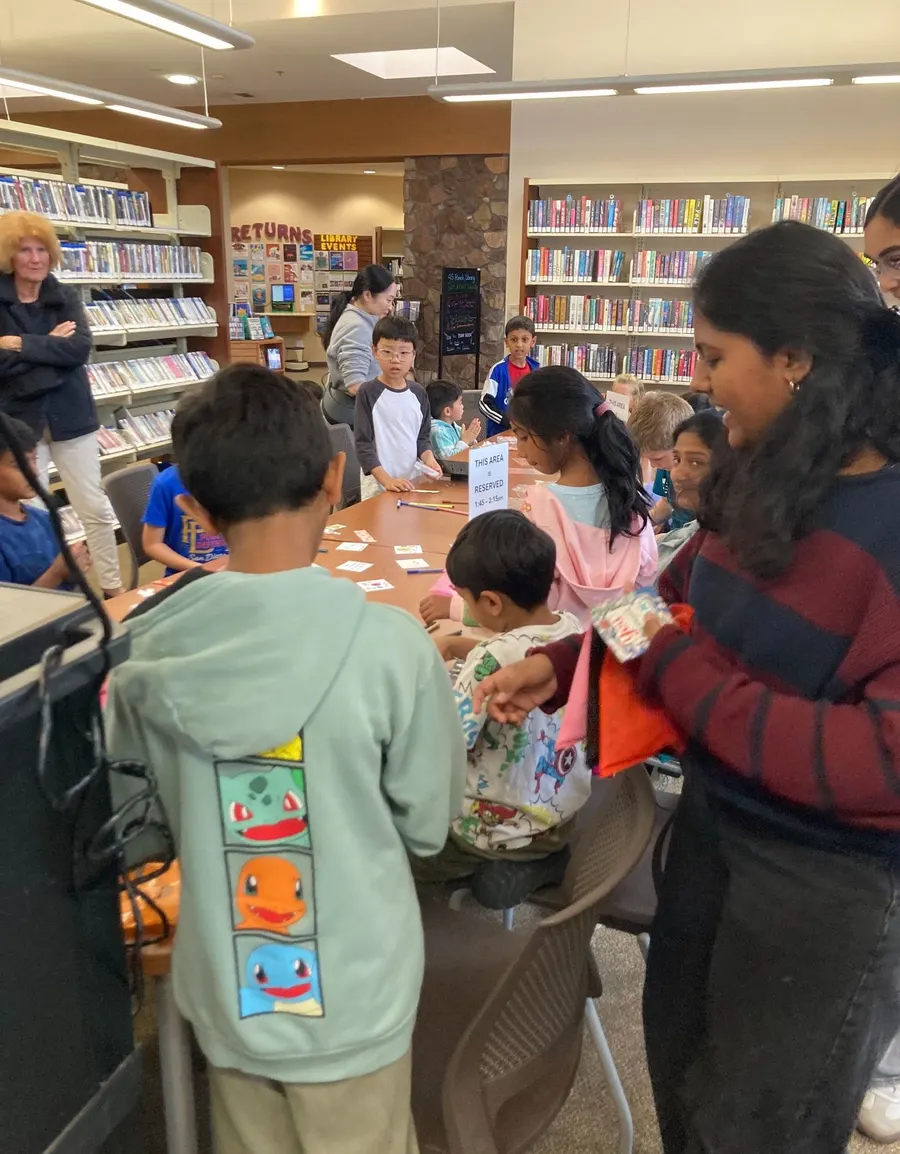 A volunteer helps a young student through a first aid activity