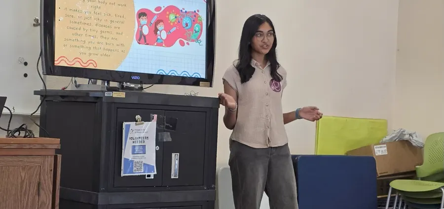 A volunteer presents beside the hand-drawn immune system poster