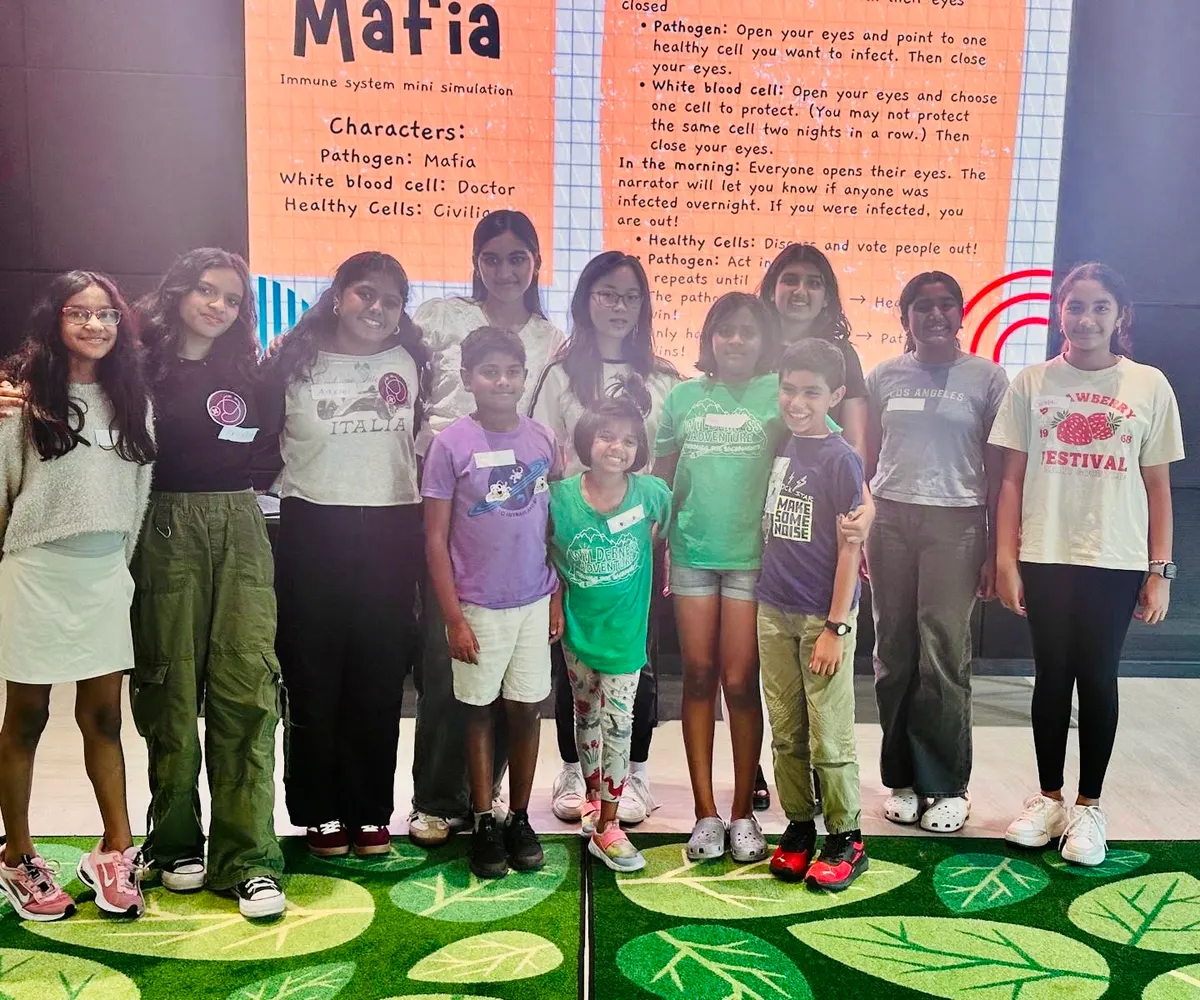 Volunteers and children in front of the poster explaining the immune system Mafia game