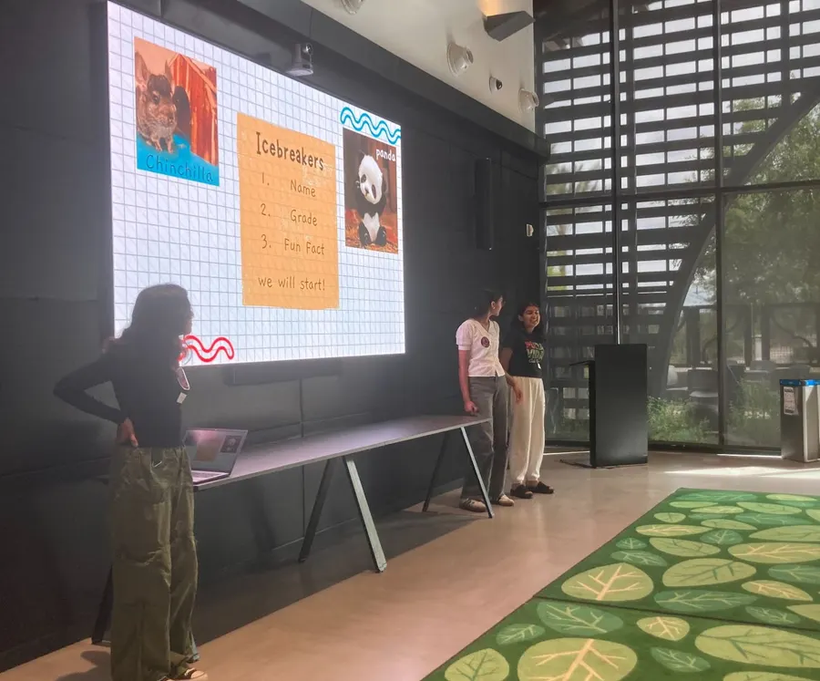 A volunteer presents beside the hand-drawn game poster