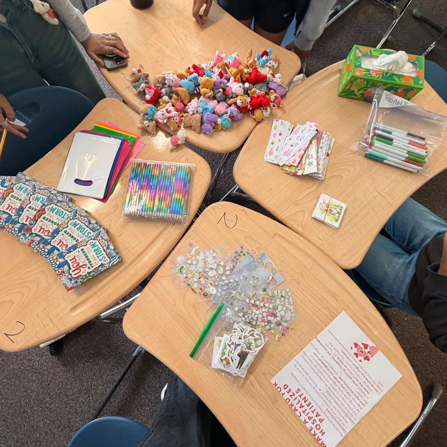 Finished cards, bracelets, and supplies laid out on the classroom desks