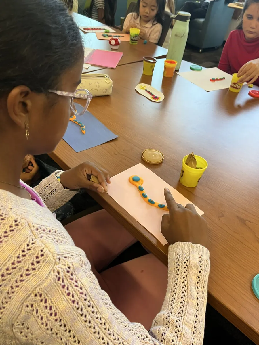 Children and volunteers making clay models around the workshop table