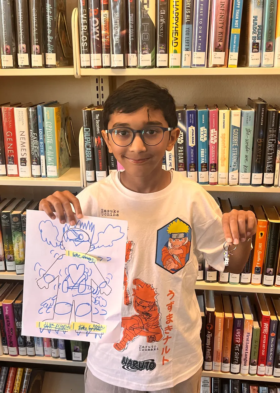 A student holds up the drawing he made during the psychology workshop