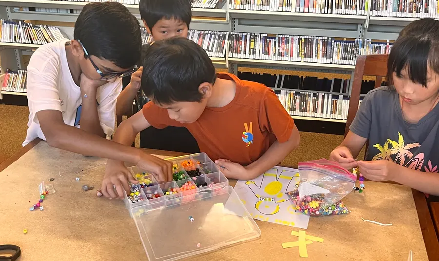 Children making beaded bracelets during the workshop activity