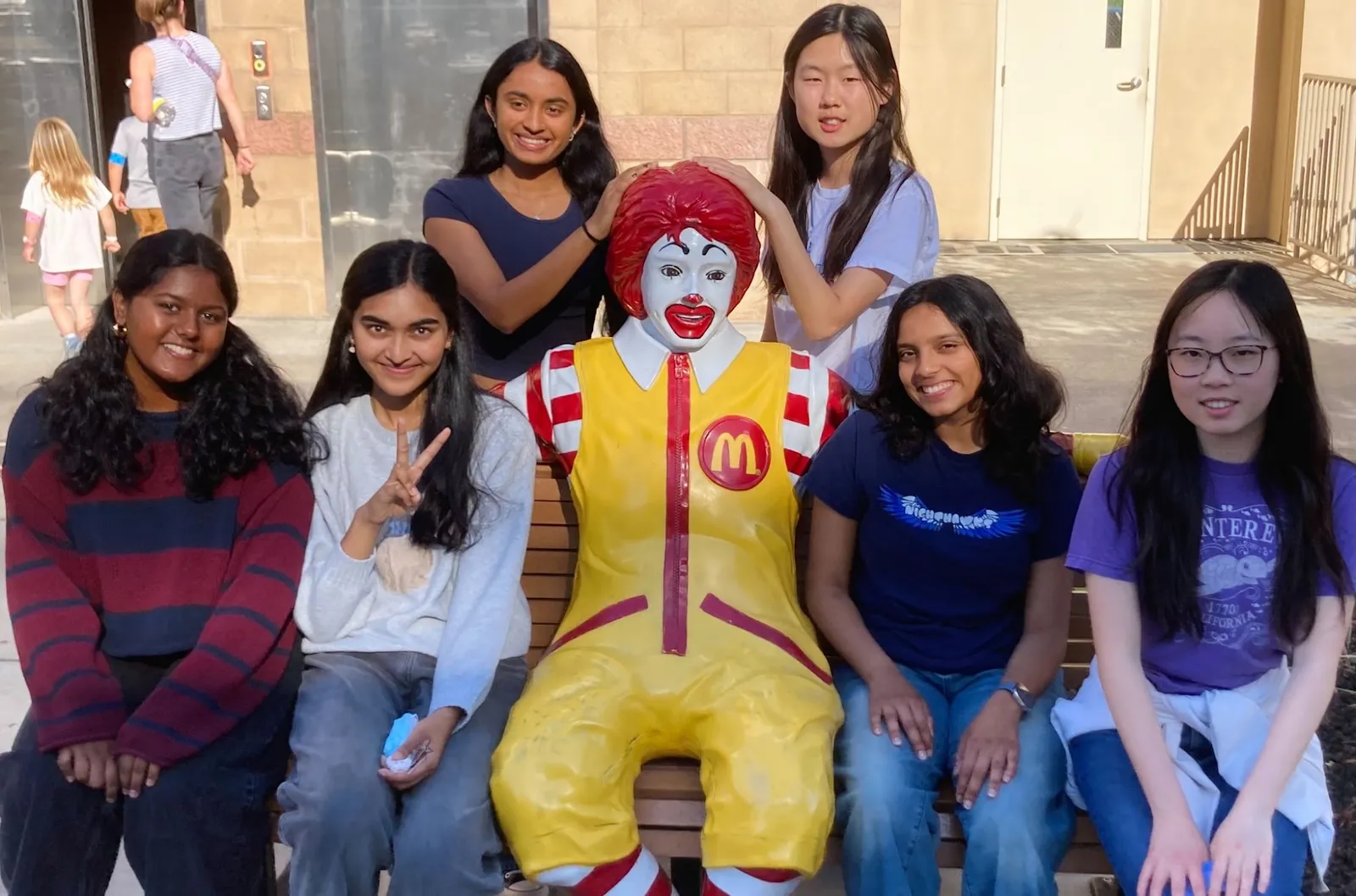 ProjectPatho members sitting with the Ronald McDonald statue outside Ronald McDonald House Charities